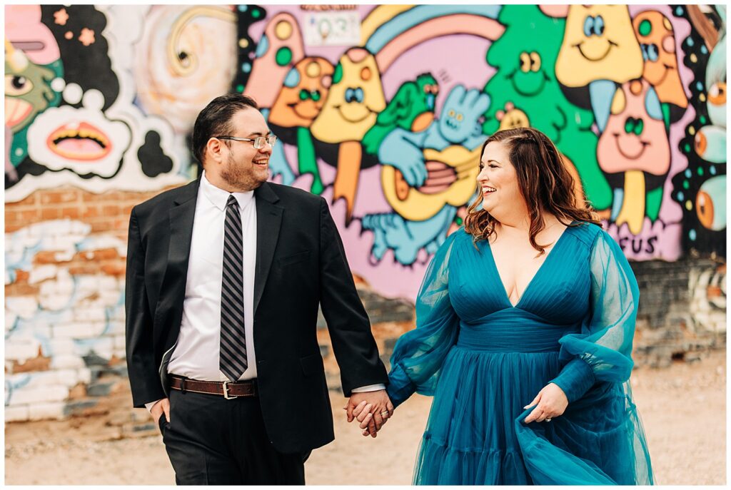 Couple standing in Freak Alley in formal outfits, surrounded by colorful street art.